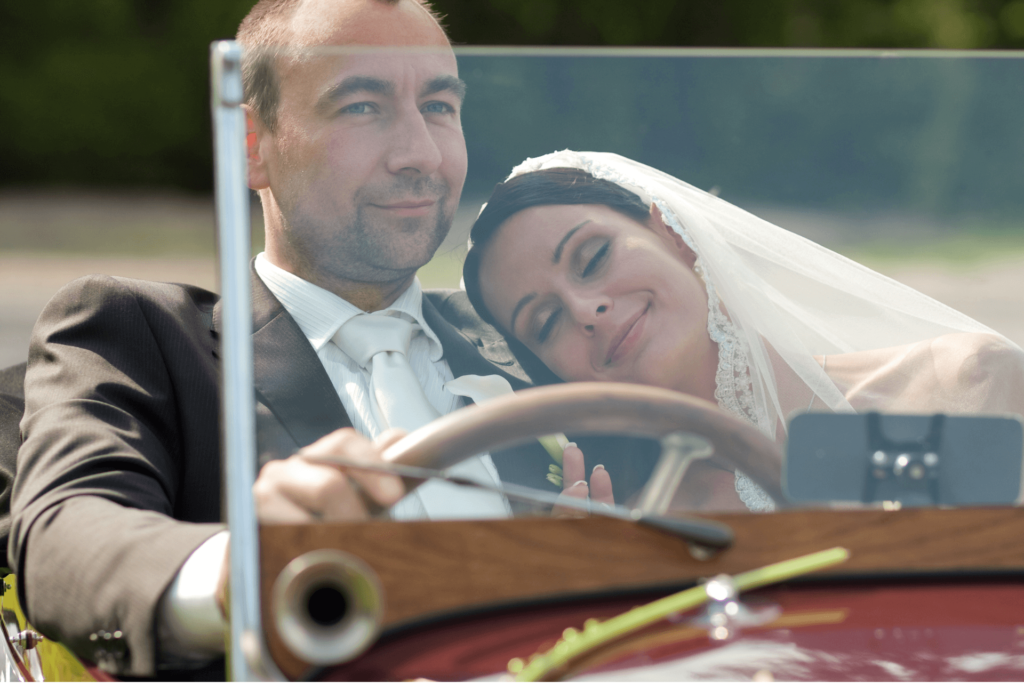 Un couple de jeunes mariés heureux dans leur voiture de mariage